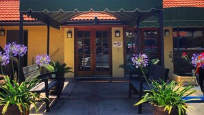 A building with a sign reading "OFFICE" above the entrance. There are potted plants and benches outside.