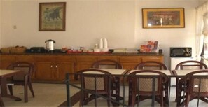 A dining area with wooden cabinets, a kitchen counter, and a dining table with chairs. - Garden Inn & Suites (Glendora)