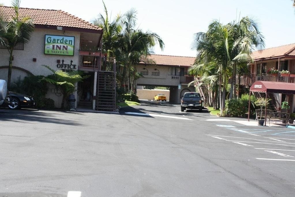 A Garden Inn hotel with a sign indicating an office, a covered parking area, and a street view with palm trees.