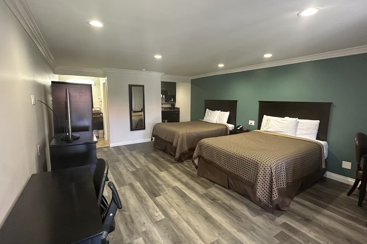 A hotel room with two beds, a desk, and a chair.