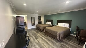 A hotel room with two beds, a desk, and a chair.