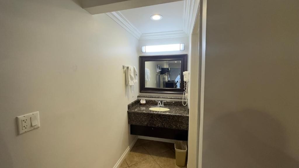 Un baño con un lavamanos blanco, encimera oscura y un espejo encima.