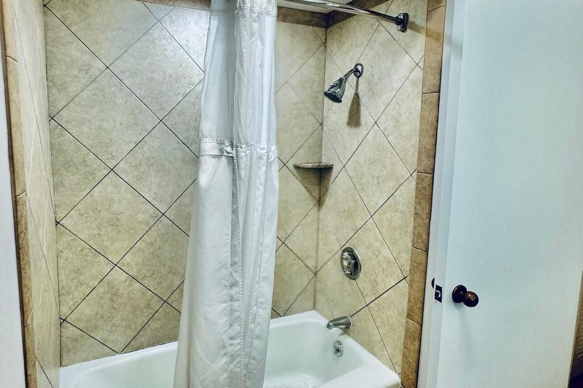 A bathroom with a bathtub, a shower, and a door.