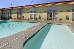 Un hôtel doté d’un espace piscine comprenant deux piscines et un bâtiment avec de nombreuses fenêtres et un toit rouge.