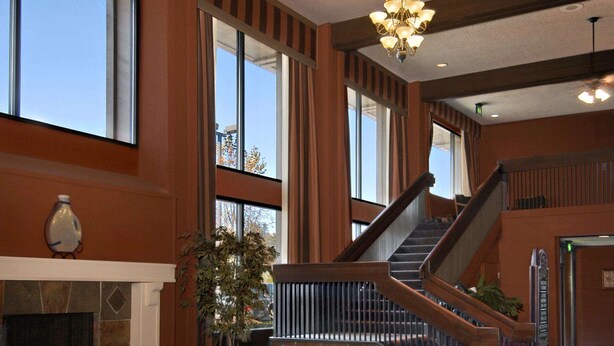 A spacious lobby with a fireplace, seating area, and a staircase leading to an upper level.
