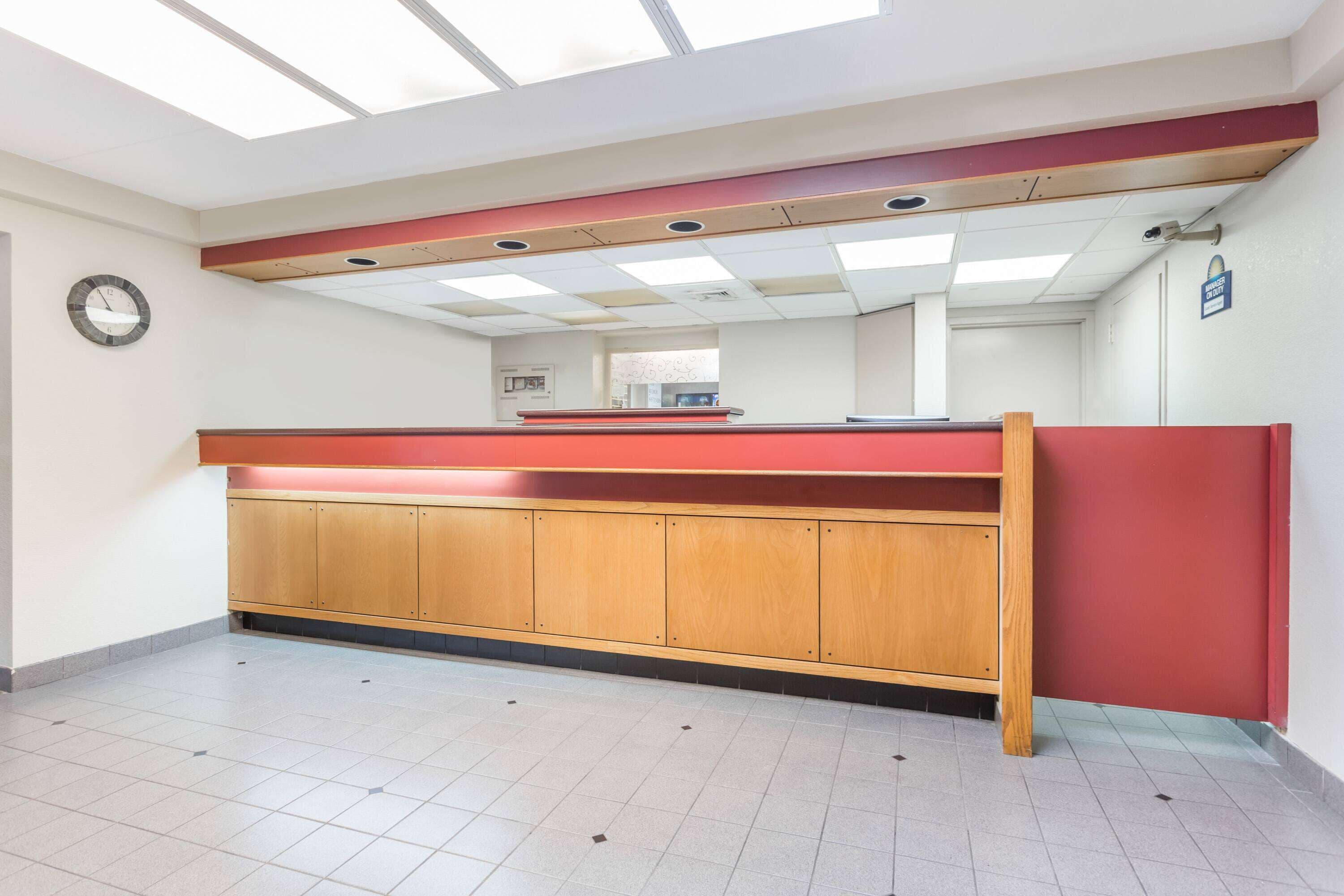 A reception area with a red counter, wooden cabinets, a clock on the wall, and a ceiling with skylights.
