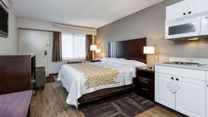 A hotel room with a bed, bedside lamps, a microwave, and a small kitchenette. - Days Inn by Wyndham Harrisburg North (Harrisburg)