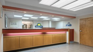 A reception area with a wooden counter, a sign for Days Inn, and a door to the right. - Days Inn by Wyndham Harrisburg North (Harrisburg)