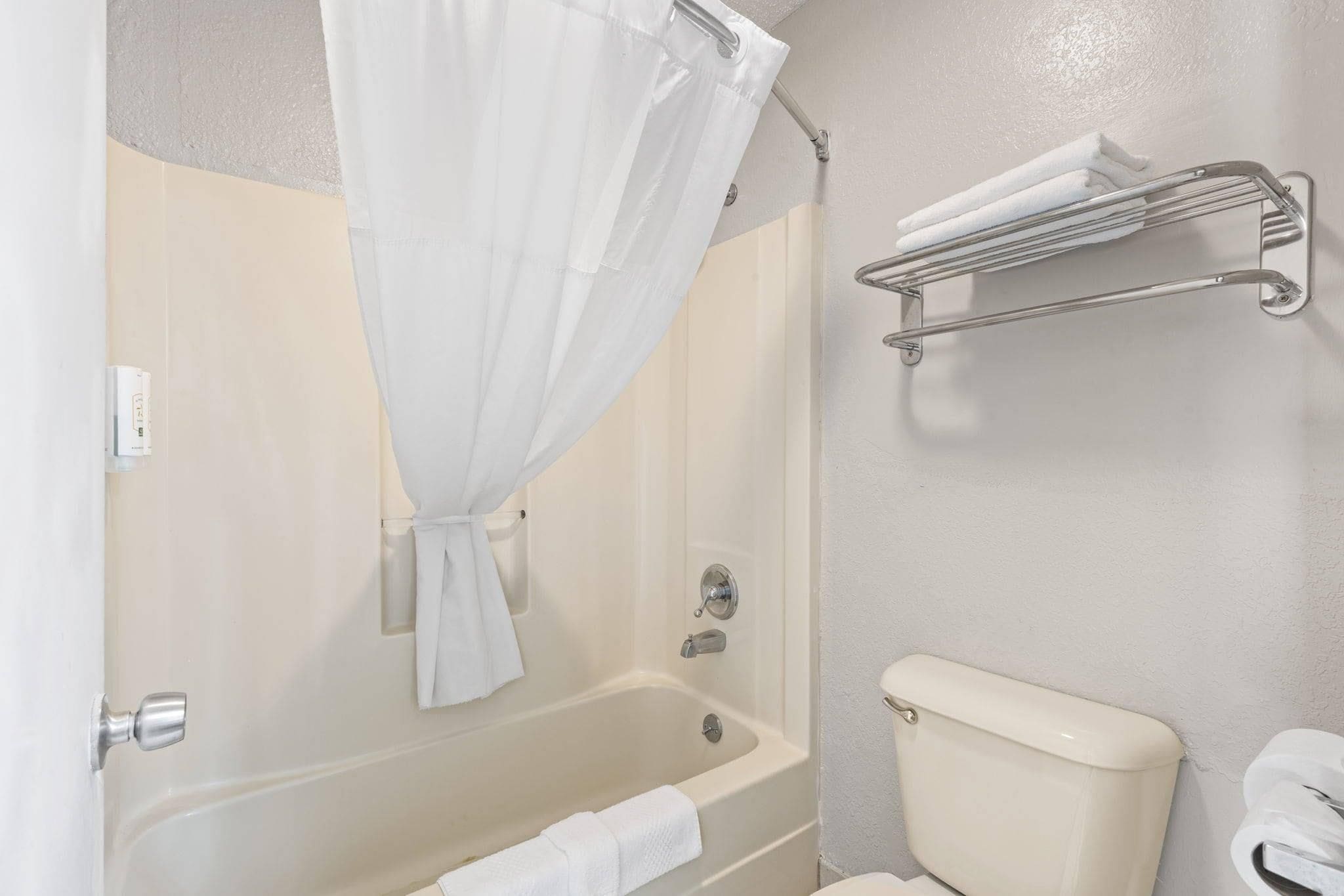 Un baño con bañera, inodoro y cortina de ducha.