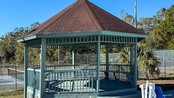 A gazebo with a triangular roof and a fenced perimeter.