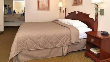 A hotel room with a bed, a nightstand, a lamp, and a mirror.