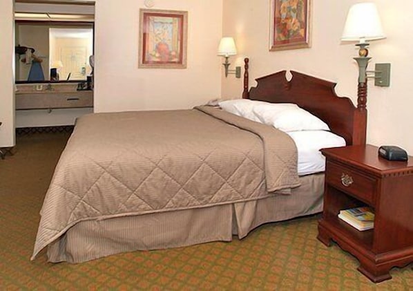 A hotel room with a bed, a nightstand, a lamp, and a mirror.