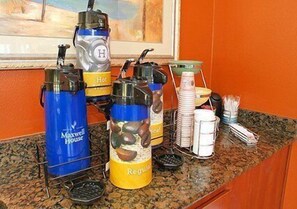 Un dispositiu de bufet amb opcions de cafè calent i normal, un dispensador de xocolata calenta i diversos plats i utensilis.