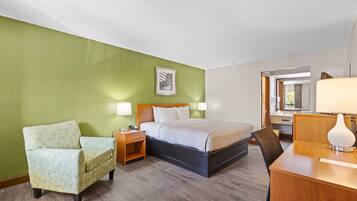 A hotel room with a bed, a chair, a desk, and a mirror.