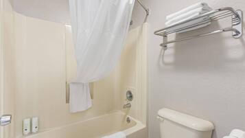 A bathroom with a bathtub, a shower curtain, a toilet, and a towel rack.