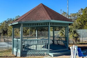 A gazebo with a triangular roof and a fenced perimeter.