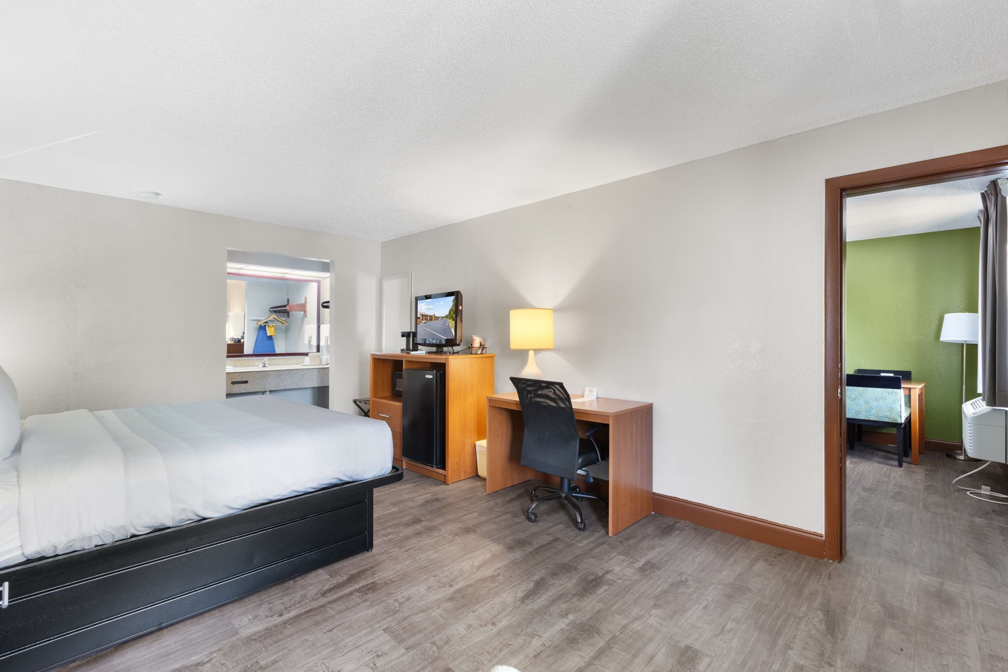 Une chambre d’hôtel avec un lit, un bureau, une chaise et un miroir.