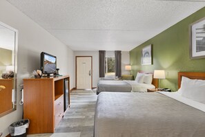 A hotel room with two beds, a desk with a television, a trash bin, and a door. - Quality Inn Crystal River (Crystal River)