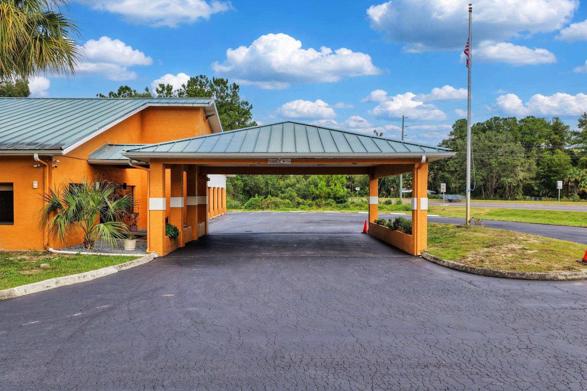 A building with a covered entrance, a parking lot, and a flagpole.
