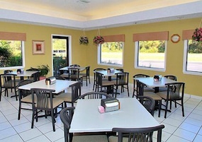 A dining area with multiple tables and chairs, a clock on the wall, and a door marked "NO EXIT".