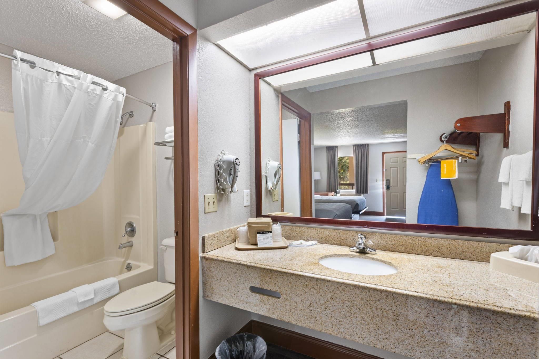 A bathroom with a bathtub, toilet, sink, and a mirror.