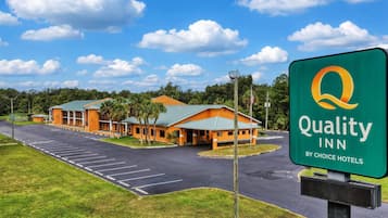 Un Quality Inn by Choice Hotels con estacionamiento y un edificio de techo verde.