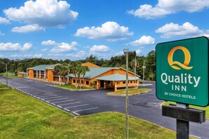 A Quality Inn by Choice Hotels with a parking lot and a building with a green roof. - Quality Inn Crystal River (Crystal River)