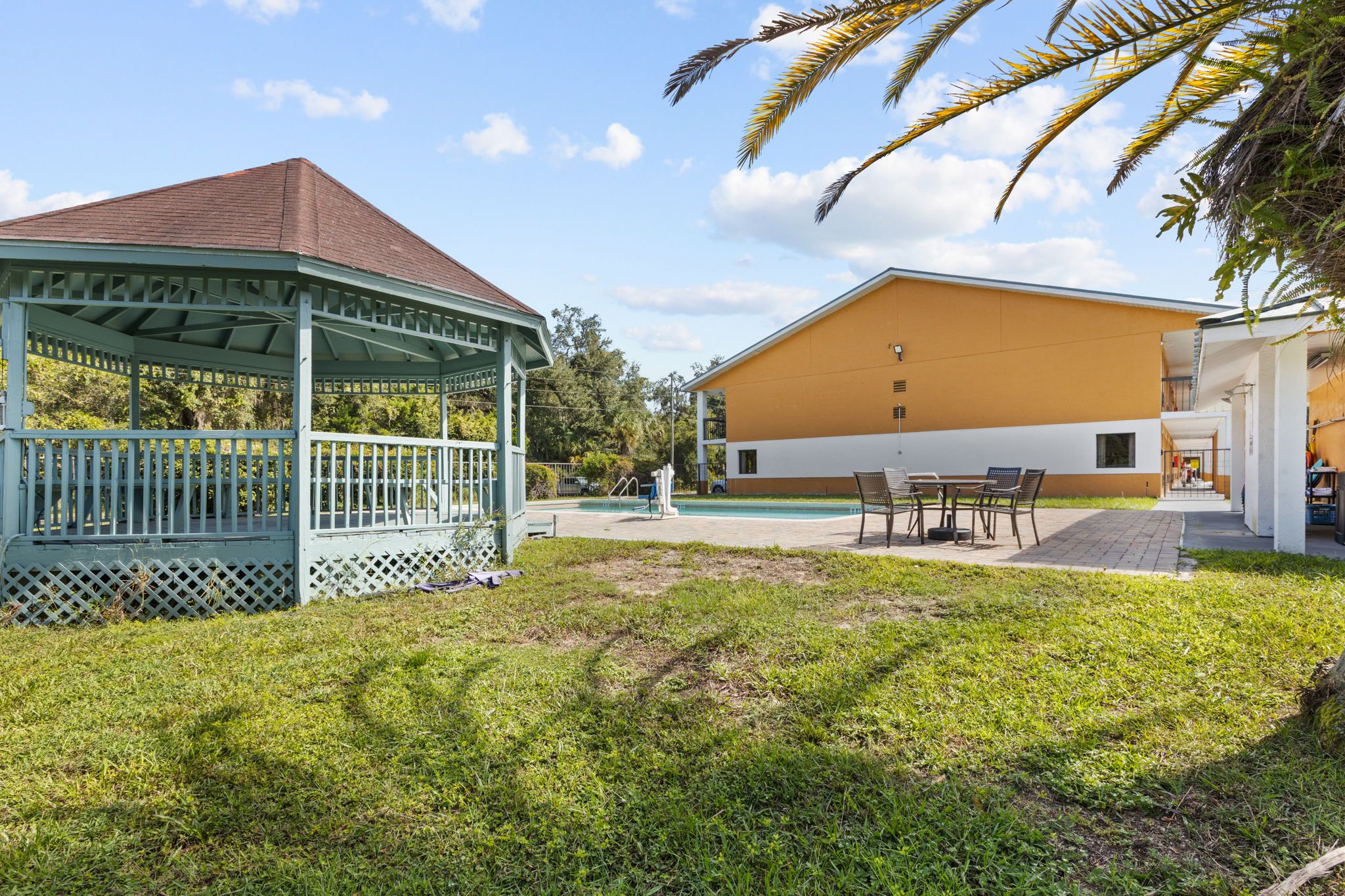 A gazebo, a pool, and a building with a flat roof.