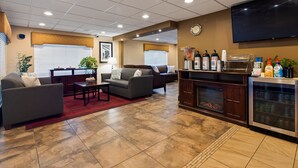 A spacious living area with sofas, a coffee station, and a fireplace. - Best Western Inn & Suites (Ontario)