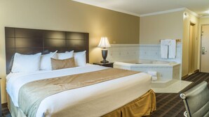 A hotel room with a large bed, a bedside lamp, a bathtub, and a chair. - Best Western Inn & Suites (Ontario)