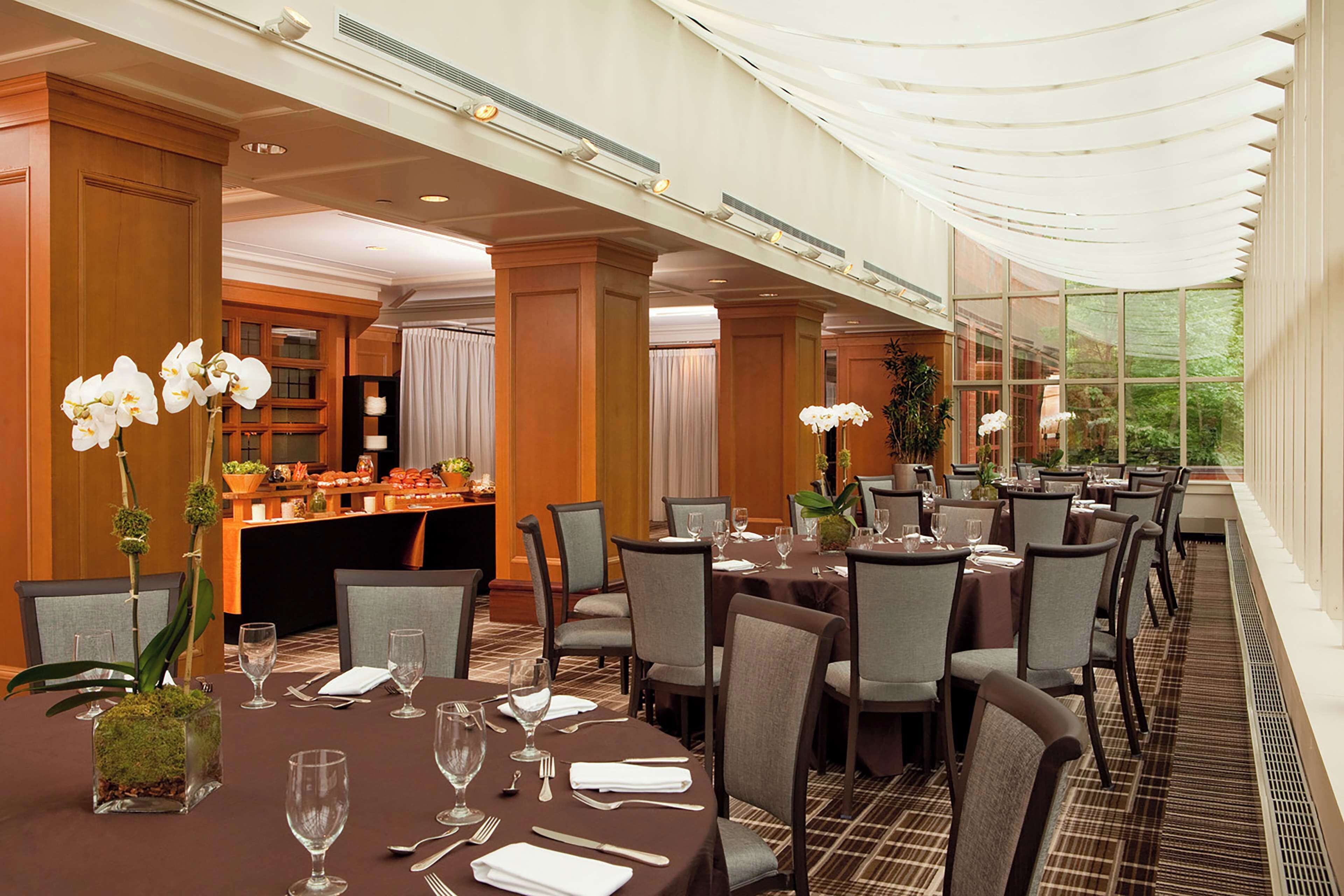 A hotel dining area with tables set for guests, featuring a buffet and a view of the outdoors.