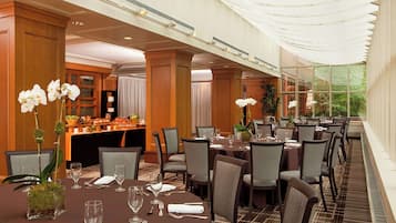 A hotel dining area with tables set for guests, featuring a buffet and a view of the outdoors.