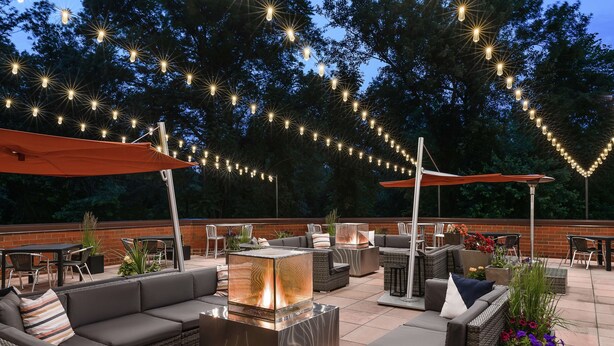 An outdoor patio with seating, a fire feature, and string lights.