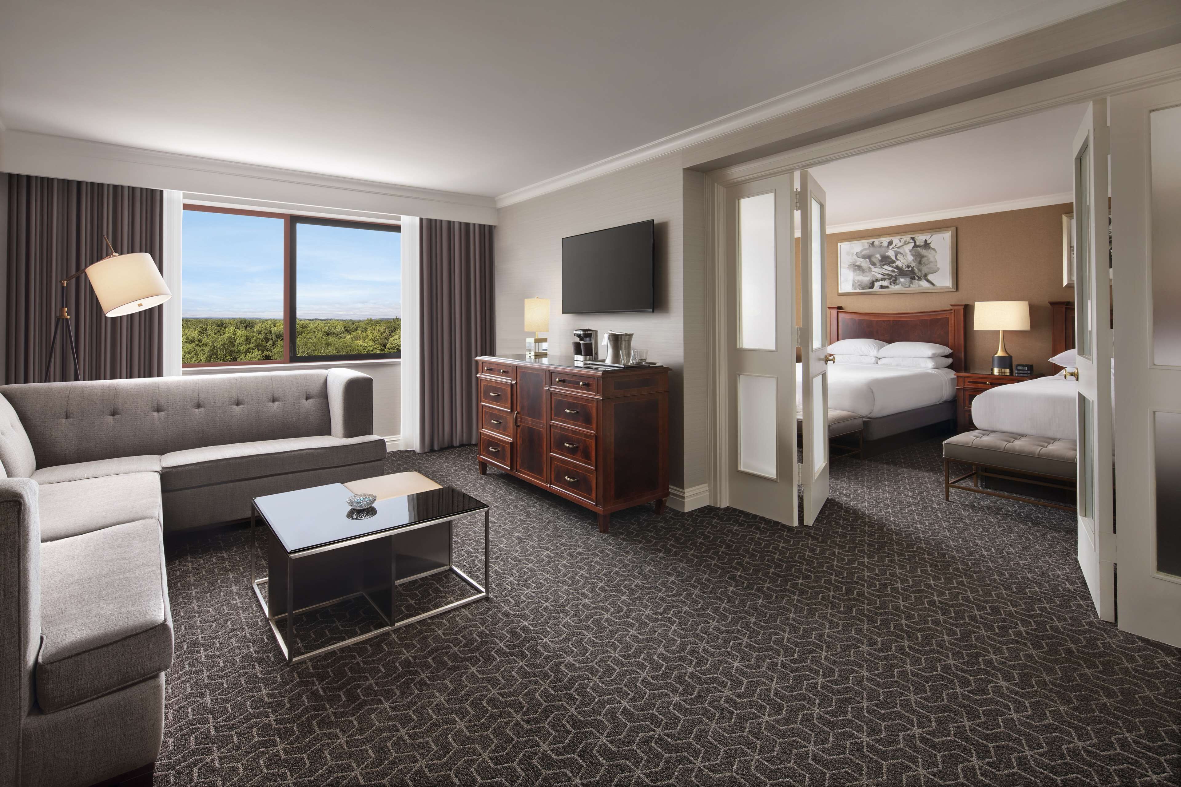 A hotel room with a sofa, a coffee table, a dresser, a bed, and a TV.