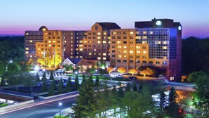 A multi-story hotel with a modern design, featuring a prominent glass facade and multiple illuminated windows.
