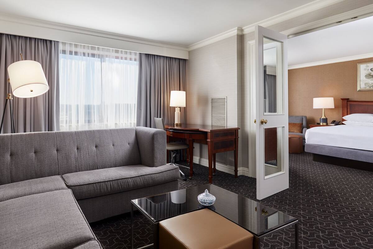 A hotel room with a sofa, a desk, a bed, and a mirror.