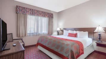 Habitación de hotel con una cama grande, dos lámparas de noche, un escritorio con televisor y una ventana con cortinas.