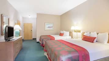 Une chambre d’hôtel avec deux lits, un téléviseur posé sur une commode et une porte.