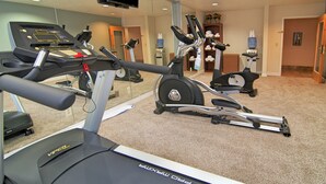 A gym with treadmills, elliptical machines, and a mirrored wall.
