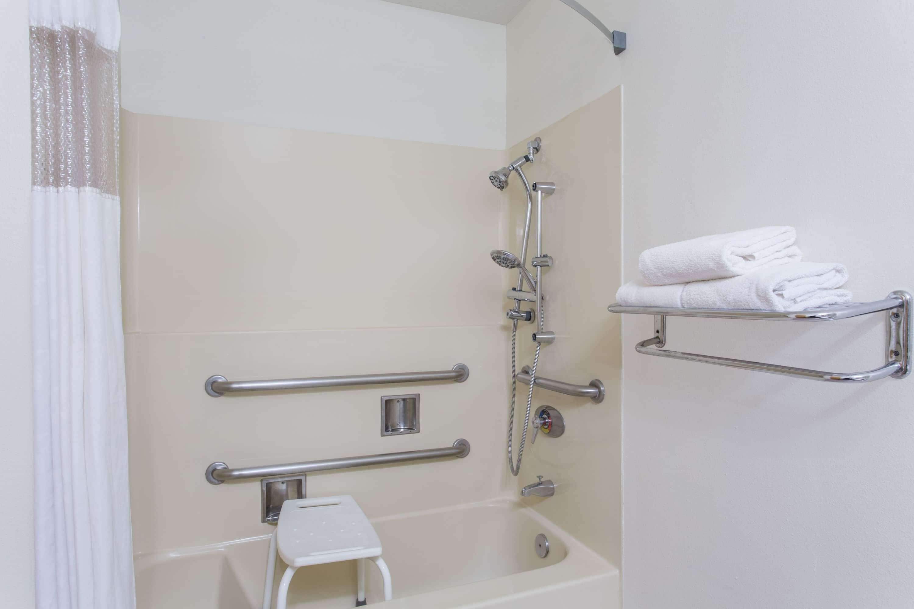 Un baño con bañera, ducha y un toallero blanco.