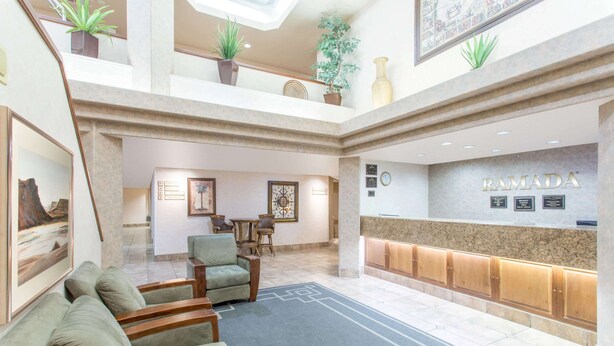 A hotel lobby with a reception desk, seating area, and artwork.