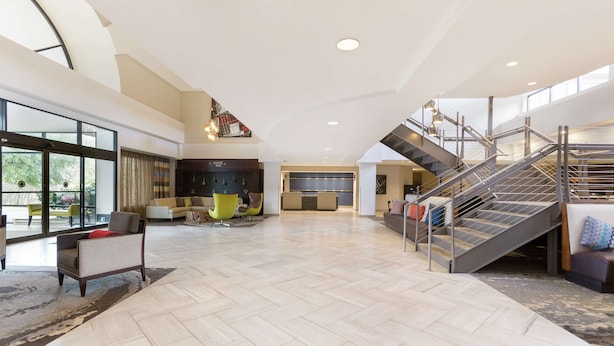 A spacious living area with a herringbone floor pattern, a staircase, and a seating area with modern furniture.