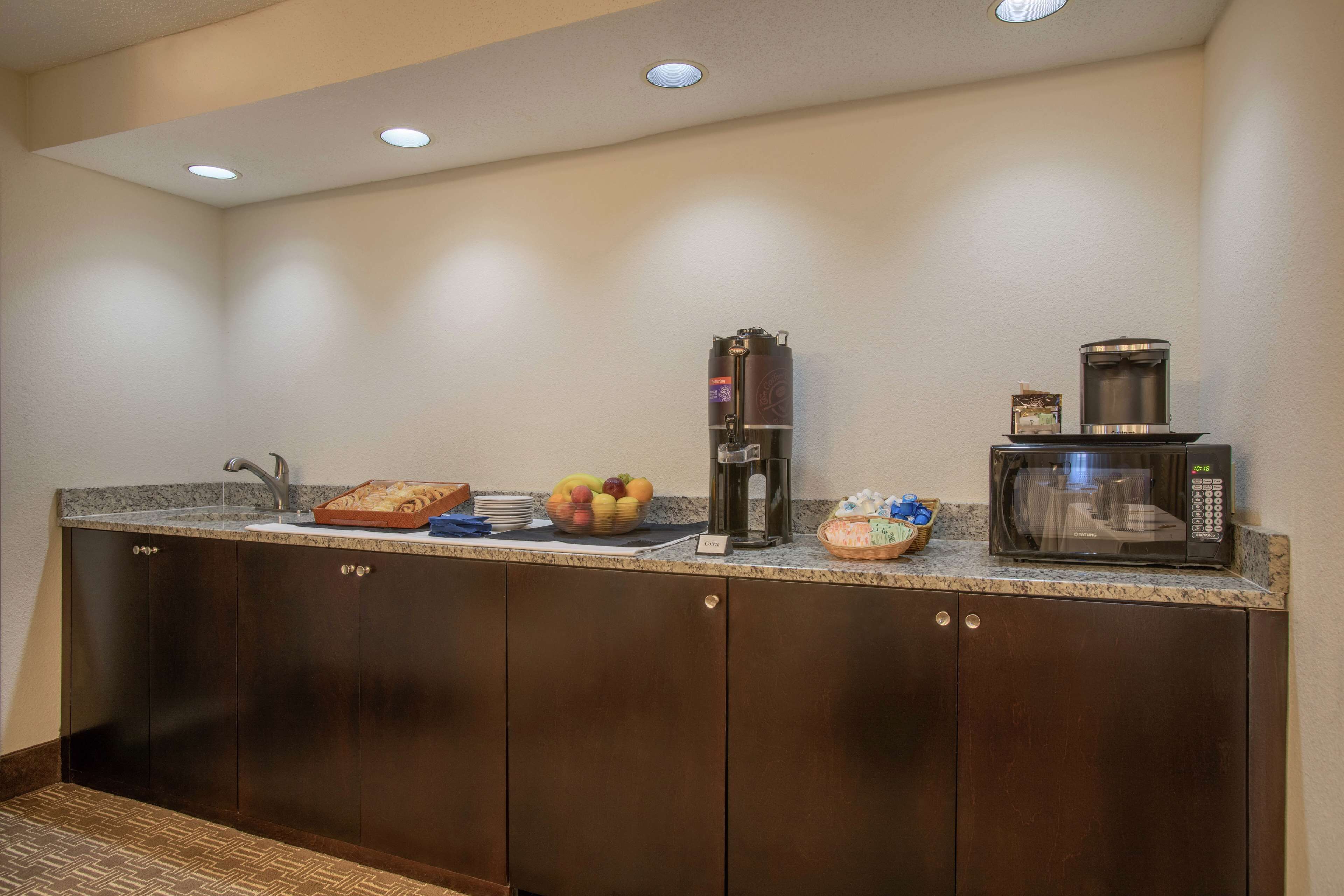 Una kitchenette equipada con microondas, cafetera y frutero.