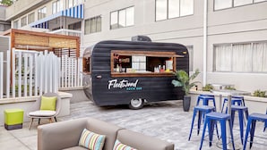 A Fleetwood patio bar with outdoor seating, including a sofa and bar stools, set against a building with large windows.