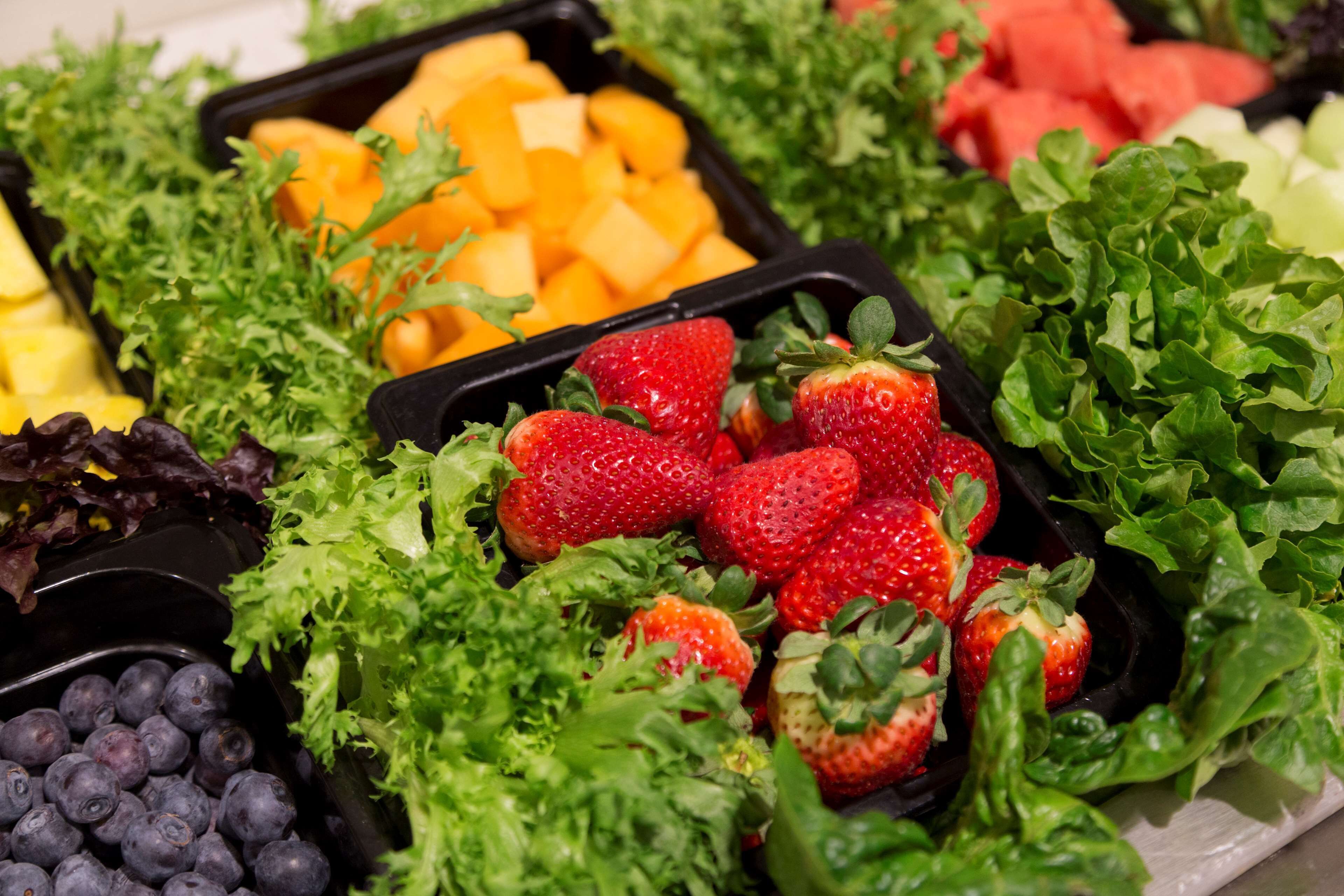 A variety of fresh fruits and vegetables in black containers.