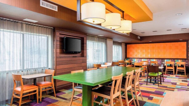 A conference room with a long table, multiple chairs, a flat-screen TV, and a colorful carpet. - Fairfield Inn & Suites Lincoln (Lincoln)