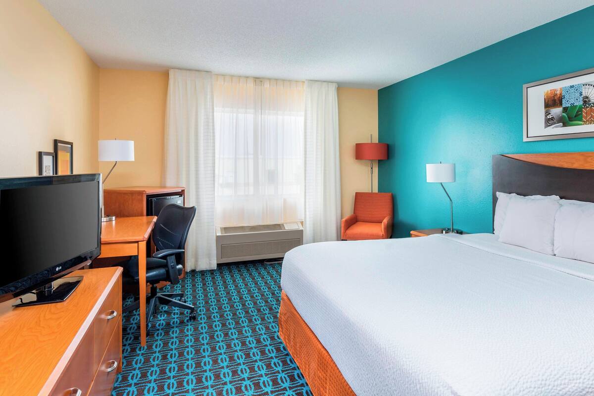 Een hotelkamer met een bed, bureau, televisie en twee stoelen.