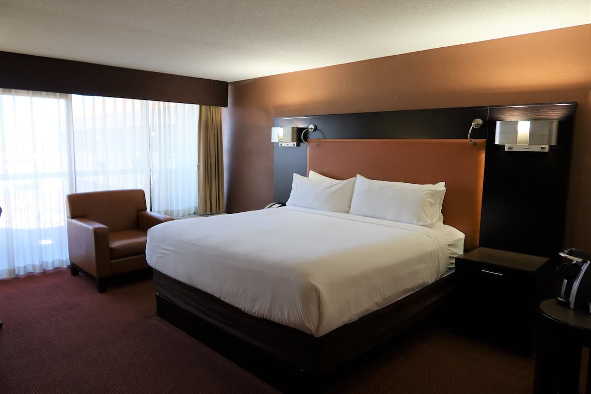 A hotel room with a large bed, a chair, a nightstand, and a water dispenser.