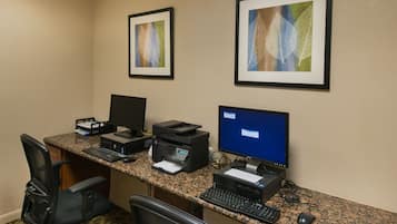 A hotel office with a desktop computer, printer, and two framed leaf artworks on the wall.