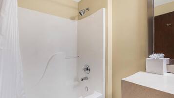 A modern bathroom with a white bathtub, a shower, and a vanity with a mirror.